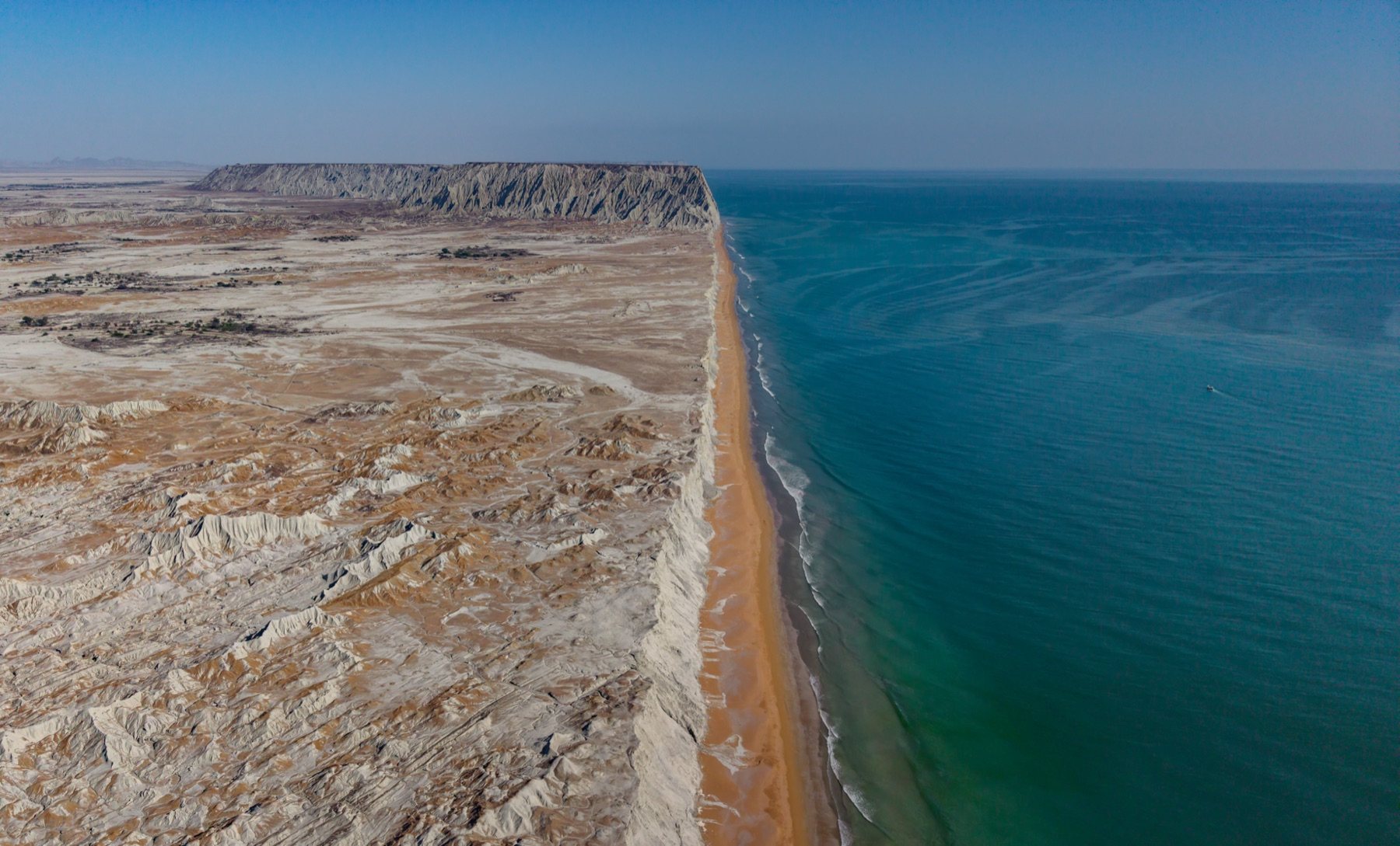 Aerial view of the badlands meeting the turquoise Arabian Sea on the Makran coast, Balochistan