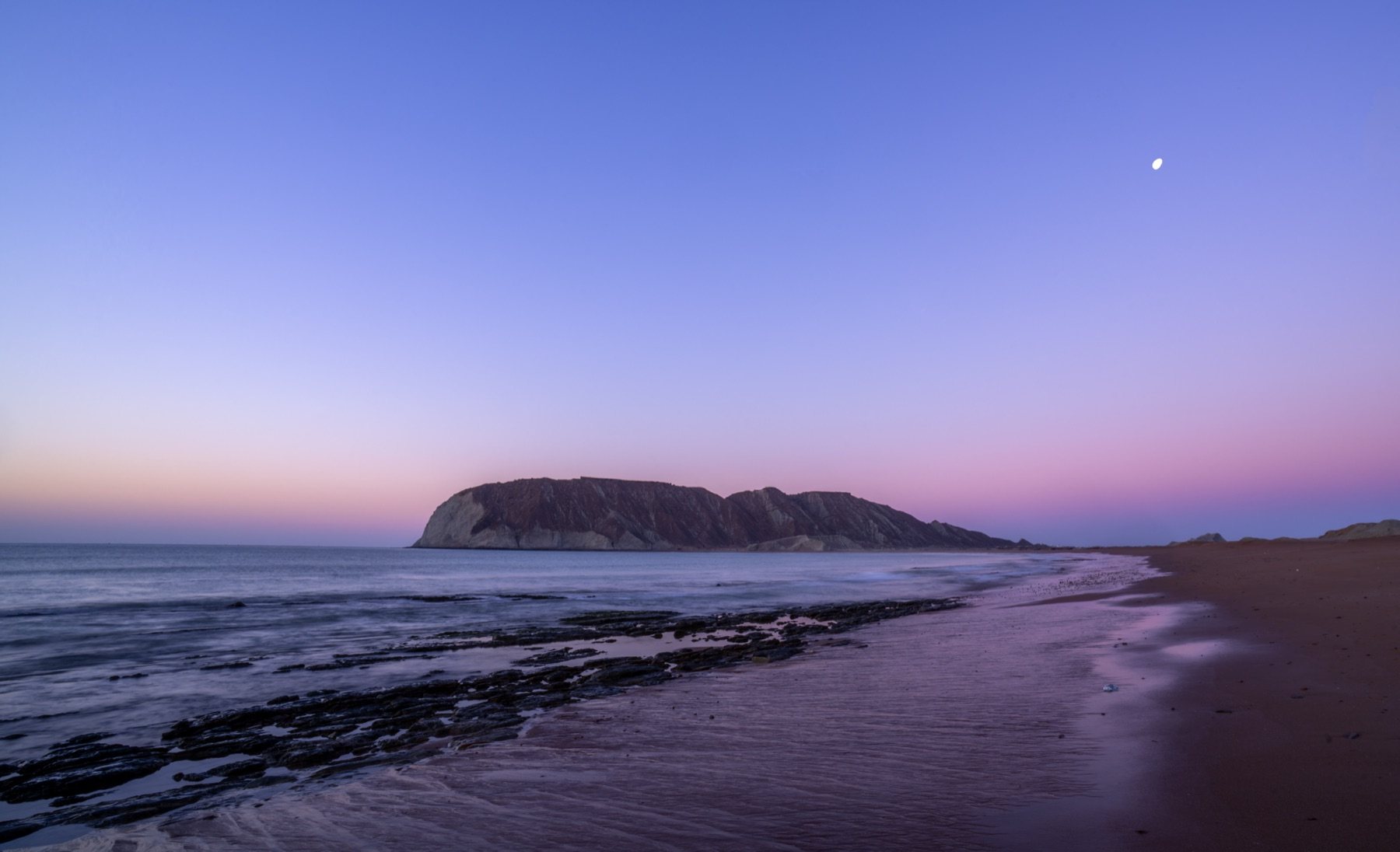 Pasni at blue hour — a rising moon over the reef and harbour