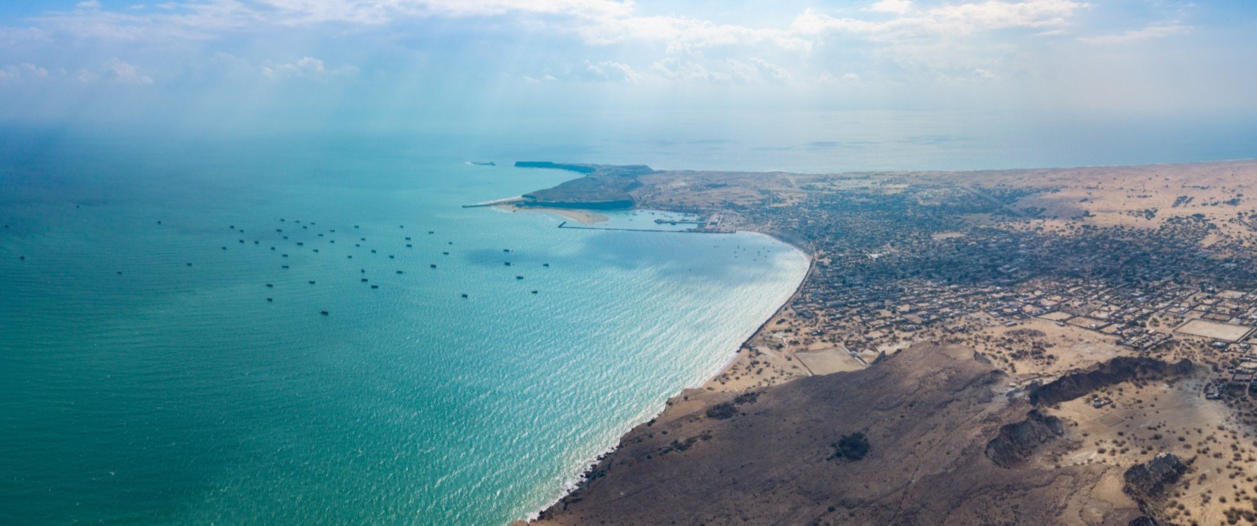 Pishukan's flat-topped hammerhead headland glowing rose-gold above a turquoise bay