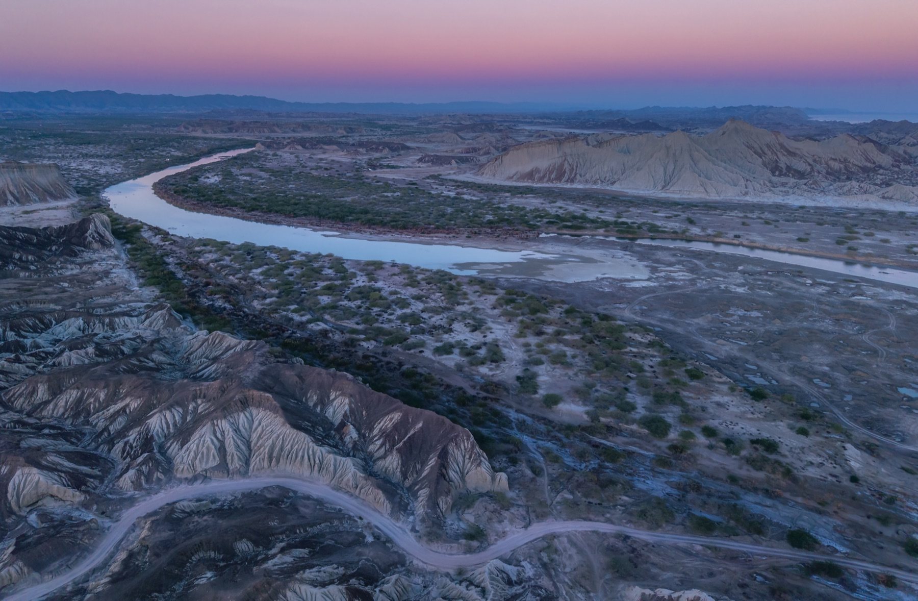 A coastal river bending through the badlands at last light on the road back from the border